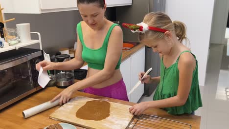 mother and daughter baking gingerbread cookies for christmas