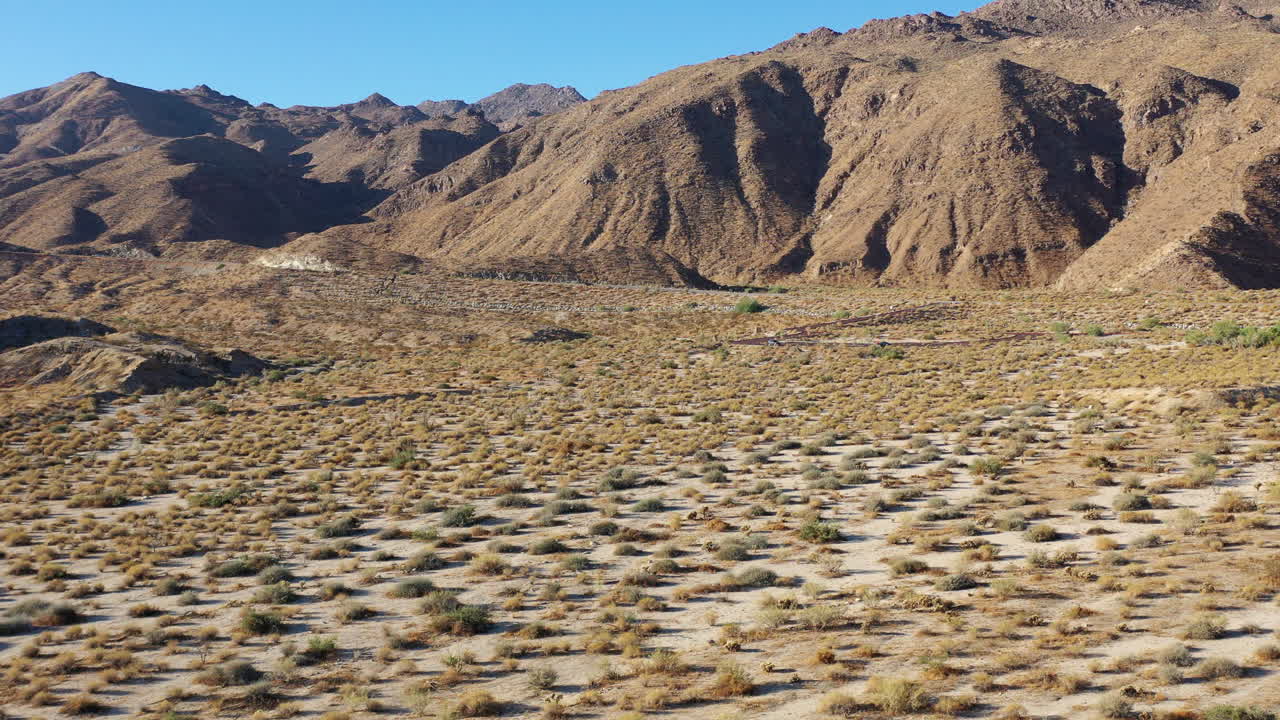 drone disparado bajo sobre el suelo de un paisaje árido que se acerca a montañas estériles cercanas