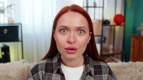 woman sitting on sofa raising eyebrows with open mouth showing shock and strong surprised reaction