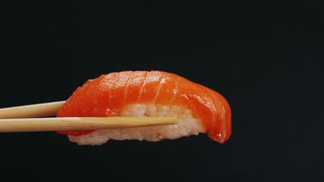 salmon sushi piece held with chopsticks