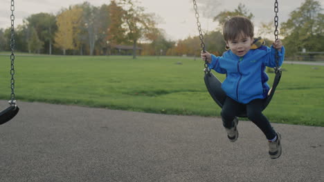 asian kid rides a swing on the playground in the park