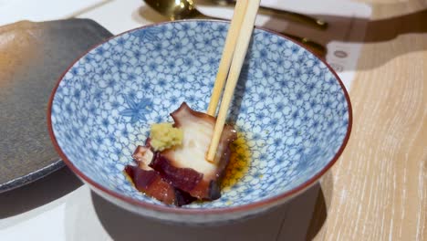 chopsticks handling squid in a patterned bowl