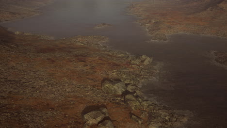 Clear-river-with-rocks-leads-towards-mountains-lit-by-sunset