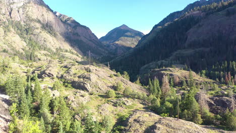 aerial drone rising motion of beautiful ouray colorado mountain range and hiking trails surrounded by thick pine tree forest and power lines in the rocky mountains