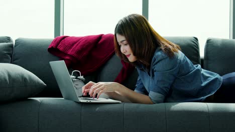 attractive asian woman enjoy relaxing time with laptop in living room home background