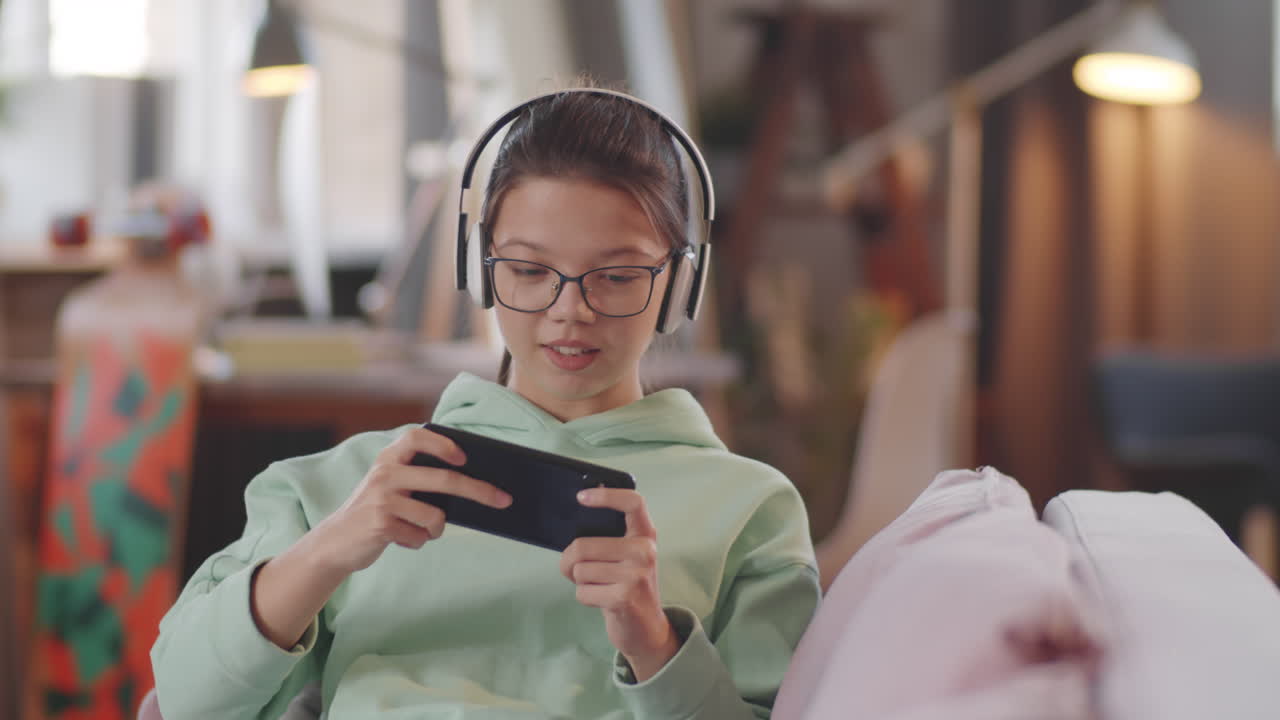 una adolescente jugando a un juego en su teléfono inteligente en casa