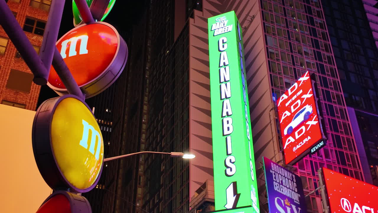 New York, USA, 2. december 2025: Natteudsigt over farverige skilte og en cannabisbutik i New York. Nærbillede af runde, oplyste logoer og et vertikalt grønt neonskilt til en cannabisbutik.
