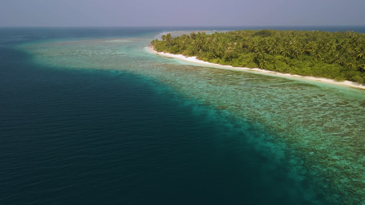 Una laguna con agua azul y una isla verde del archipiélago maldivo inmersa en ella