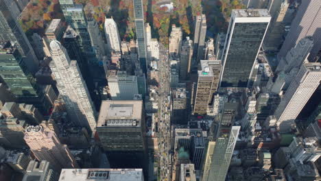 Backwards-fly-above-downtown.-Modern-skyscrapers-with-glossy-glass-facades.-Autumn-colour-trees-in-park.-Manhattan,-New-York-City,-USA