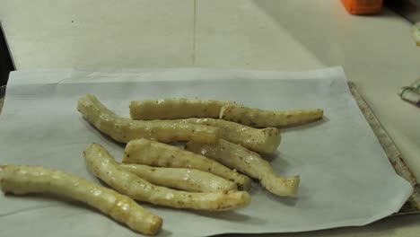 Chef-put-marinated-topinambur-root-on-tray-for-baking,close-up