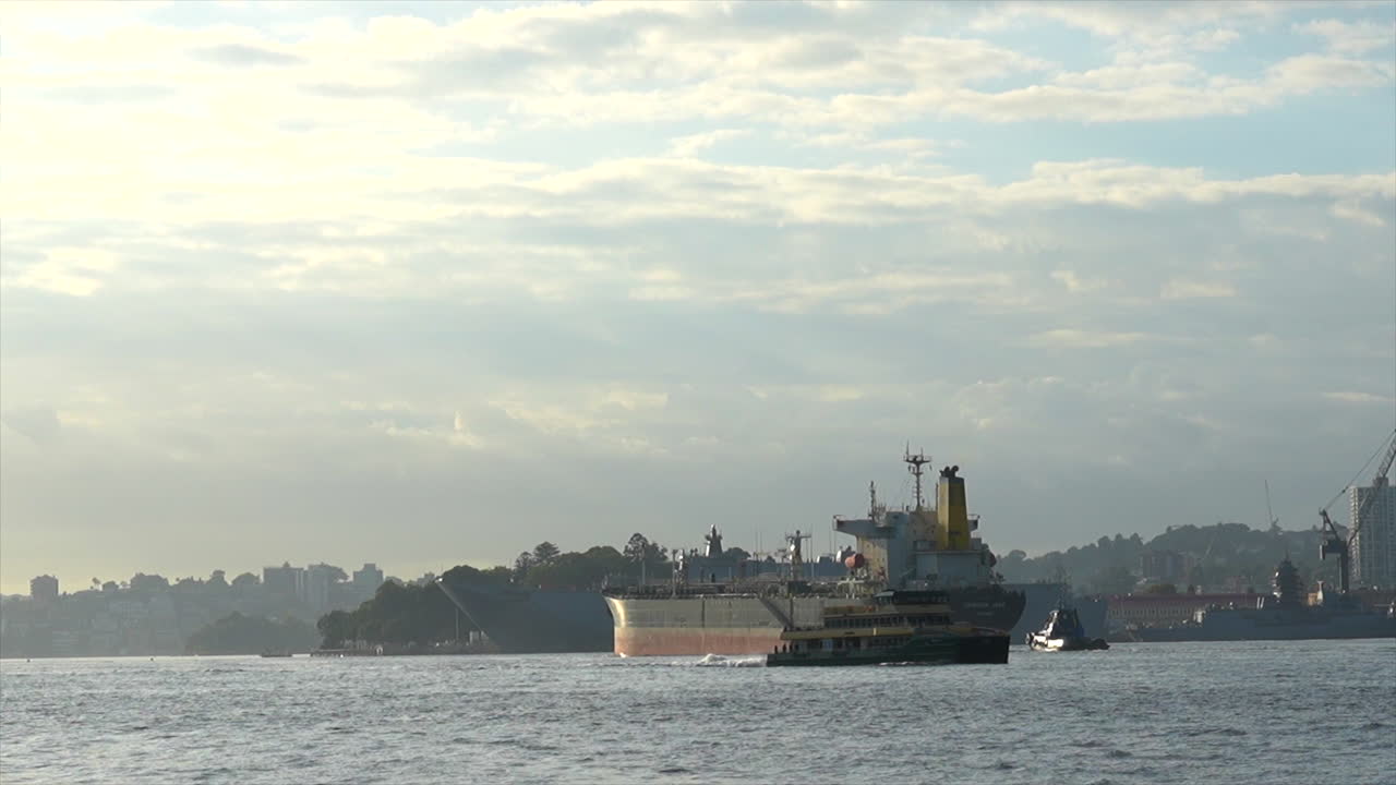 un gran buque de carga pasa por varios buques diferentes mientras sale del puerto de sydney