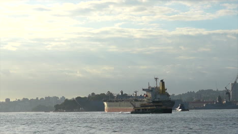 Ein-Großes-Frachtschiff-Fährt-Beim-Verlassen-Des-Hafens-Von-Sydney-An-Verschiedenen-Schiffen-Vorbei