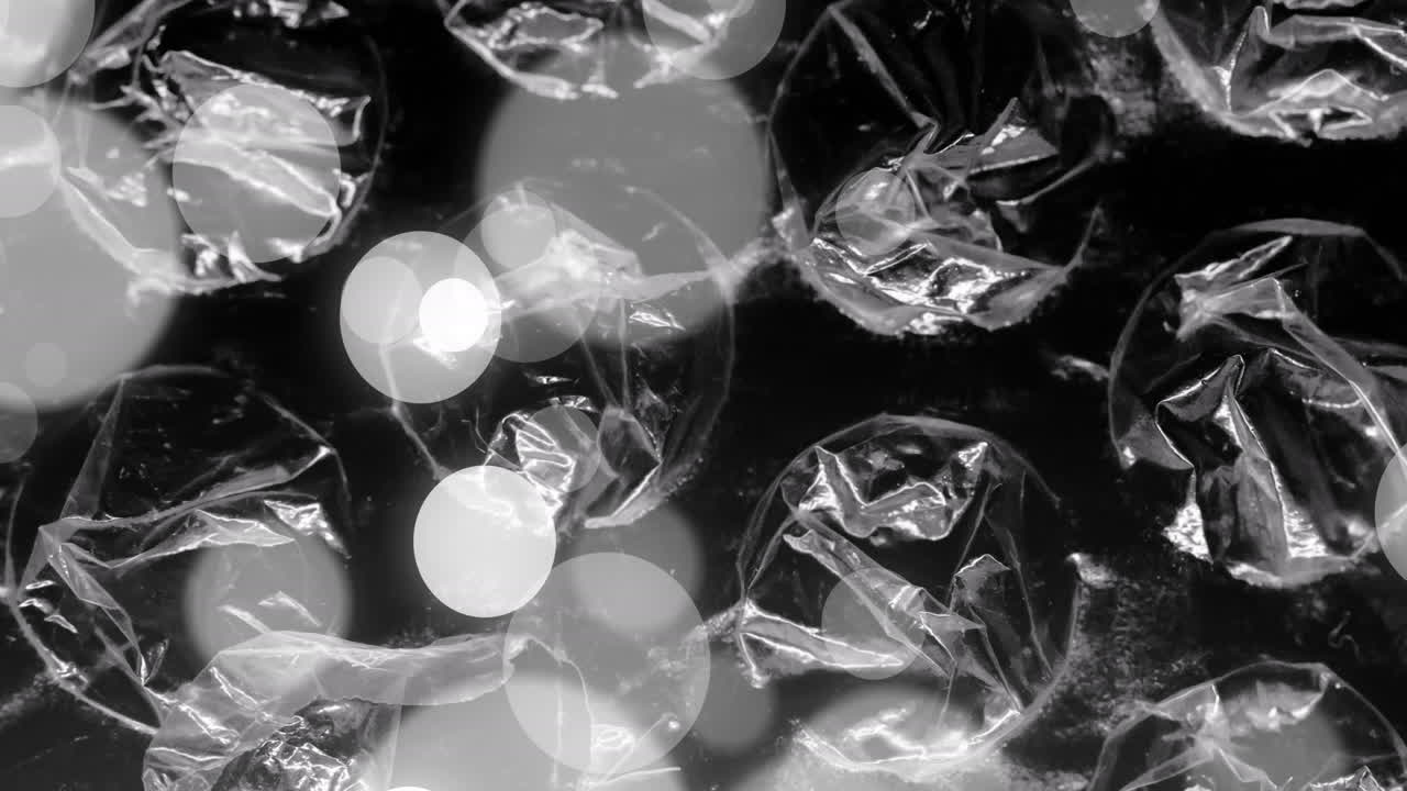 회색과 색의 보케 빛 점이 투명한 시트, 필름 및 거품 포장 위에 움직이는 애니메이션