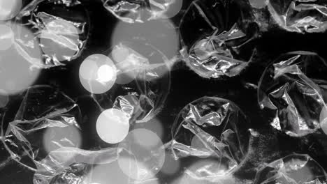 animation of grey and white bokeh light spots moving over transparent sheets, films and bubble wrap