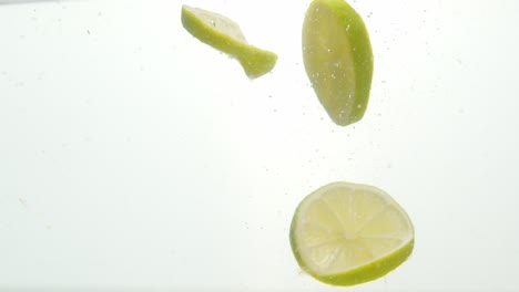 fresh green chopped lemon dropped into water isolated on white background