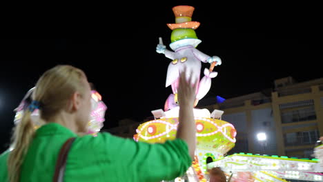 woman watching a colorful spinning amusement park ride at night