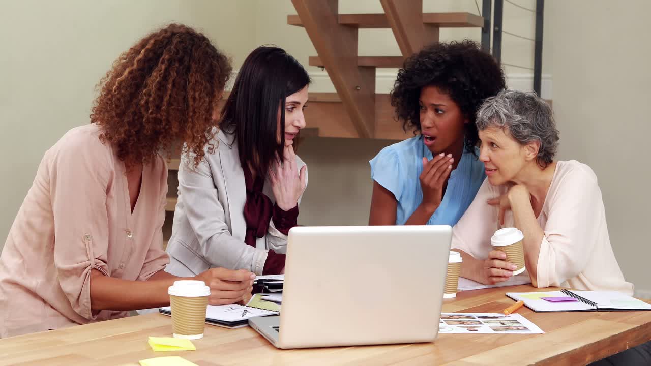 Surprised creative businesswomen whispering