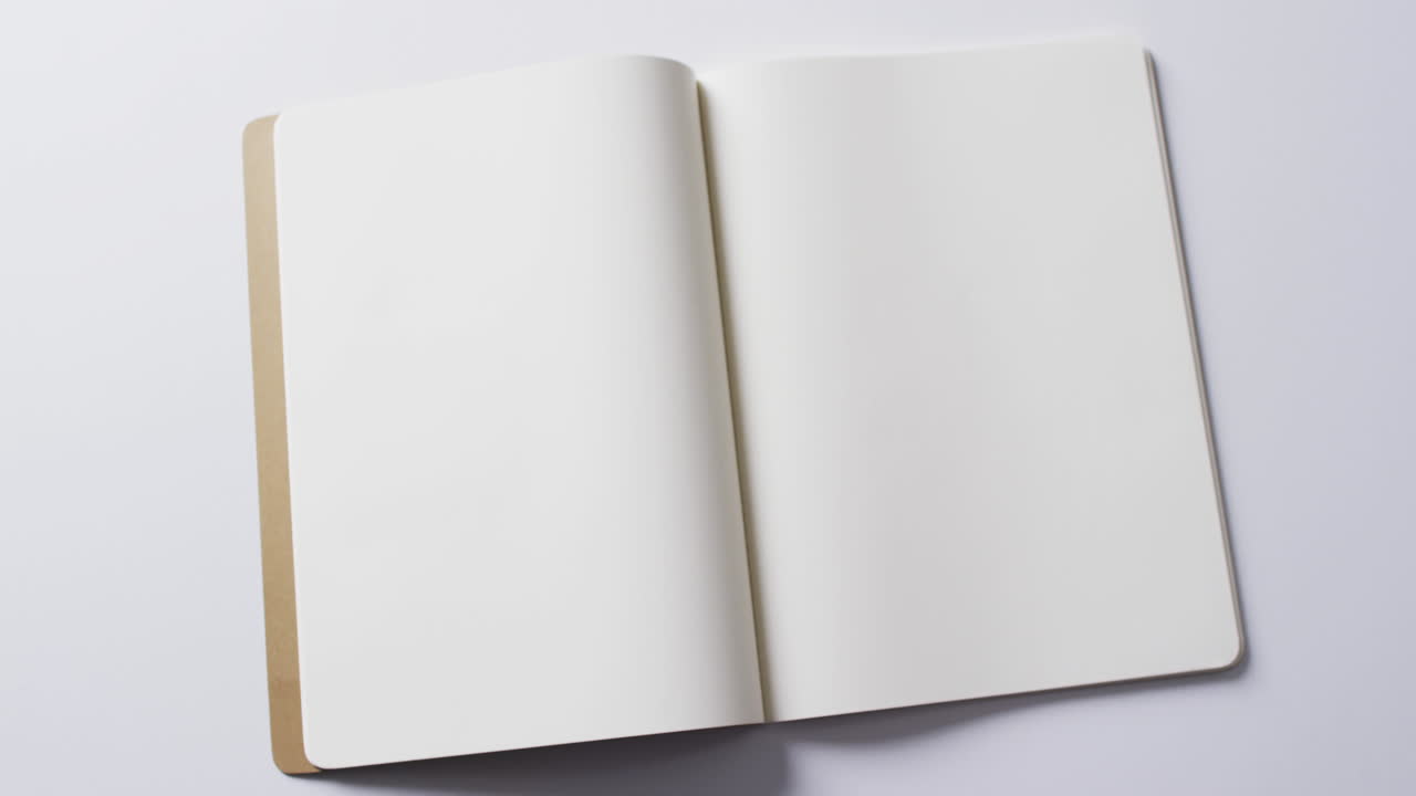 Close up of open blank book with copy space on white background in slow motion