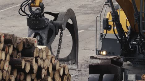 Heavy-working-machinery-at-the-sawmill,-stacking-tree-trunks-into-piles