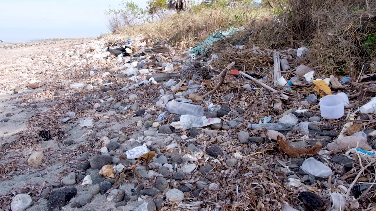 Heaps of plastic bottles and other rubbish washed up on the beach from the ocean on a tropical island