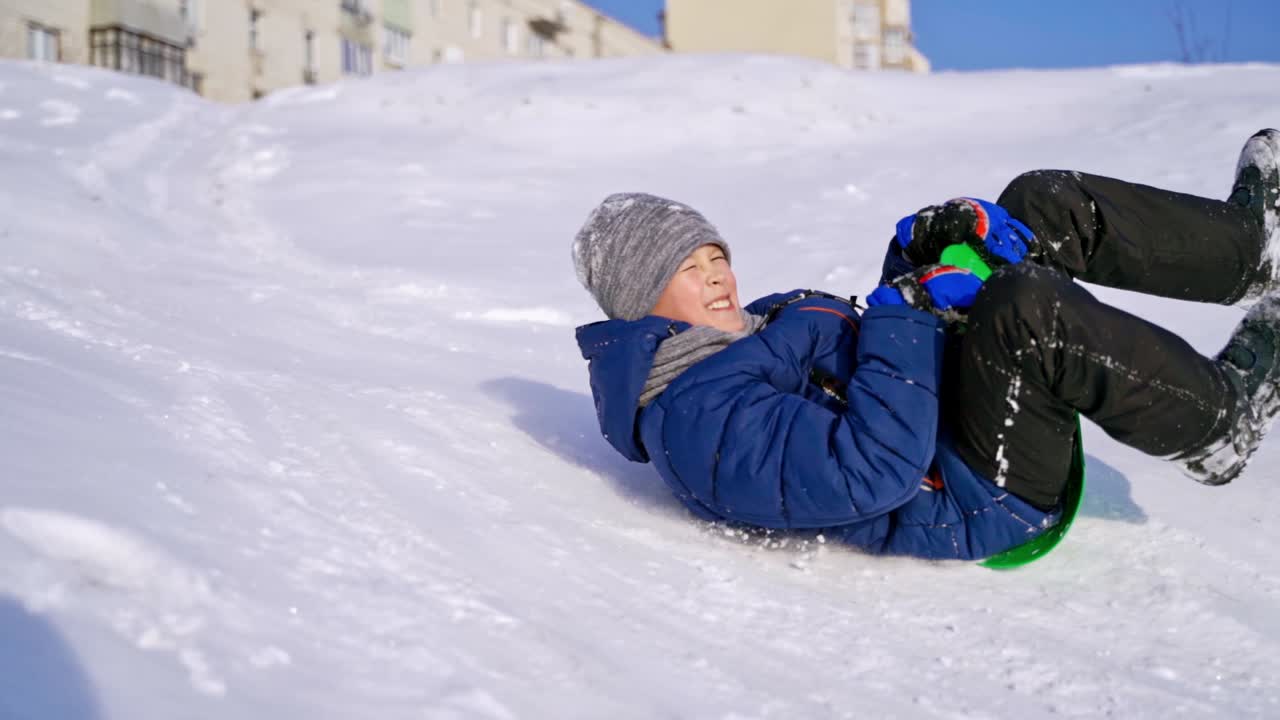 Frost winter season. Ride down the hills, winter games and fun. Kid laughing, sledging down a hill. Child rides down a hill, winter games and fun. Slow motion.