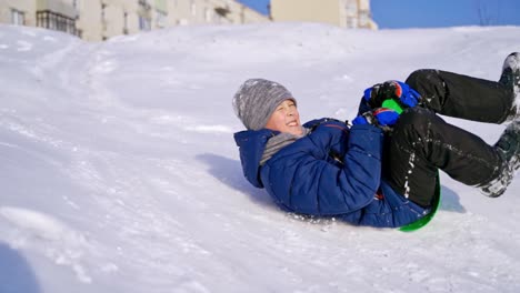 frost winter season. ride down the hills, winter games and fun. kid laughing, sledging down a hill. child rides down a hill, winter games and fun. slow motion.