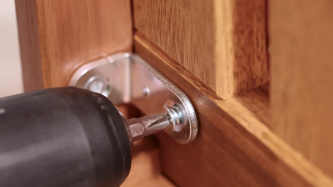 A power drill secures screws into wooden furniture, highlighting efficient assembly in a well-lit environment