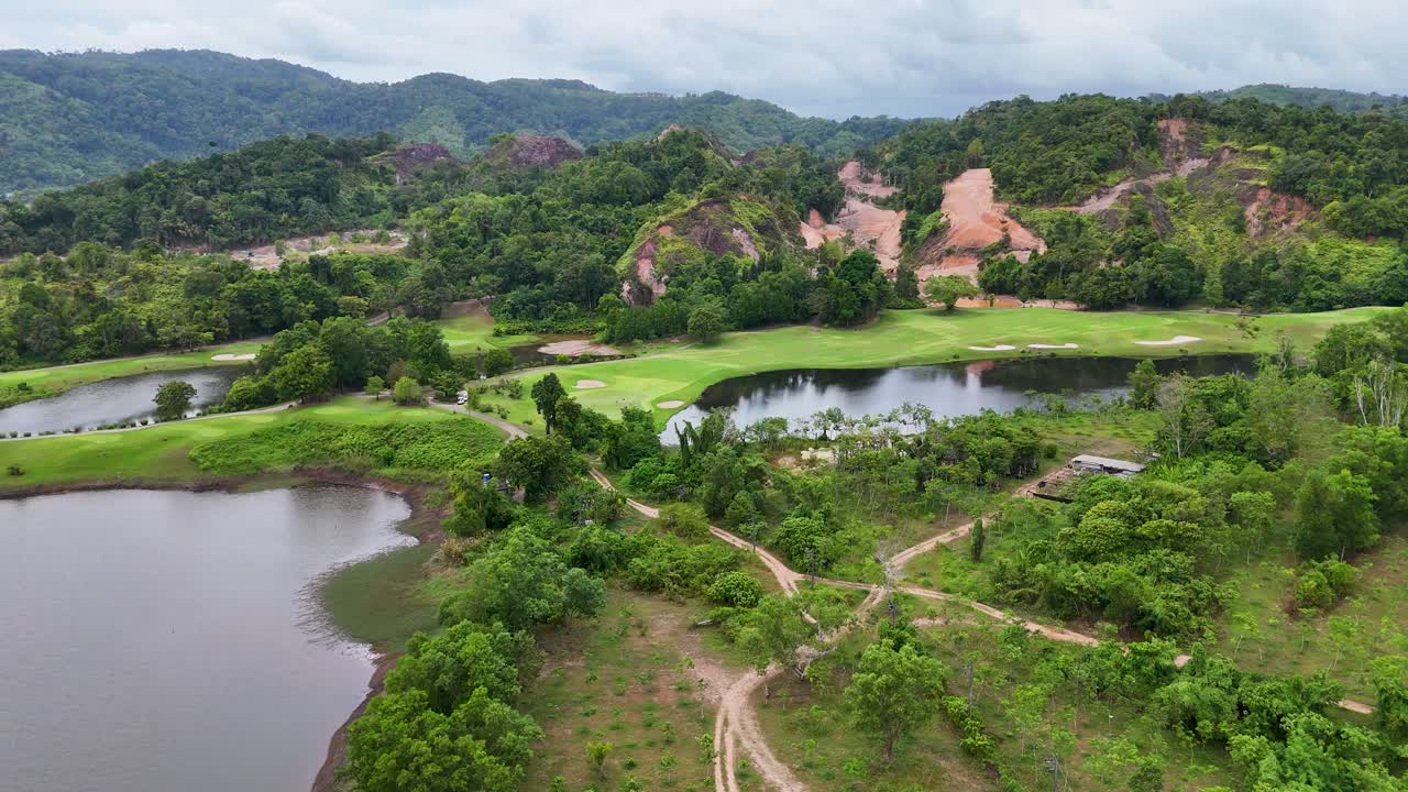 vista aérea de un exuberante campo de golf en phuket, tailandia, que muestra una vegetación vibrante, características acuáticas y acantilados rocosos bajo una iluminación suave
