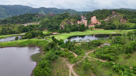 aerial view of a lush golf course in phuket, thailand, showcasing vibrant greenery, water features, and rocky cliffs under soft lighting