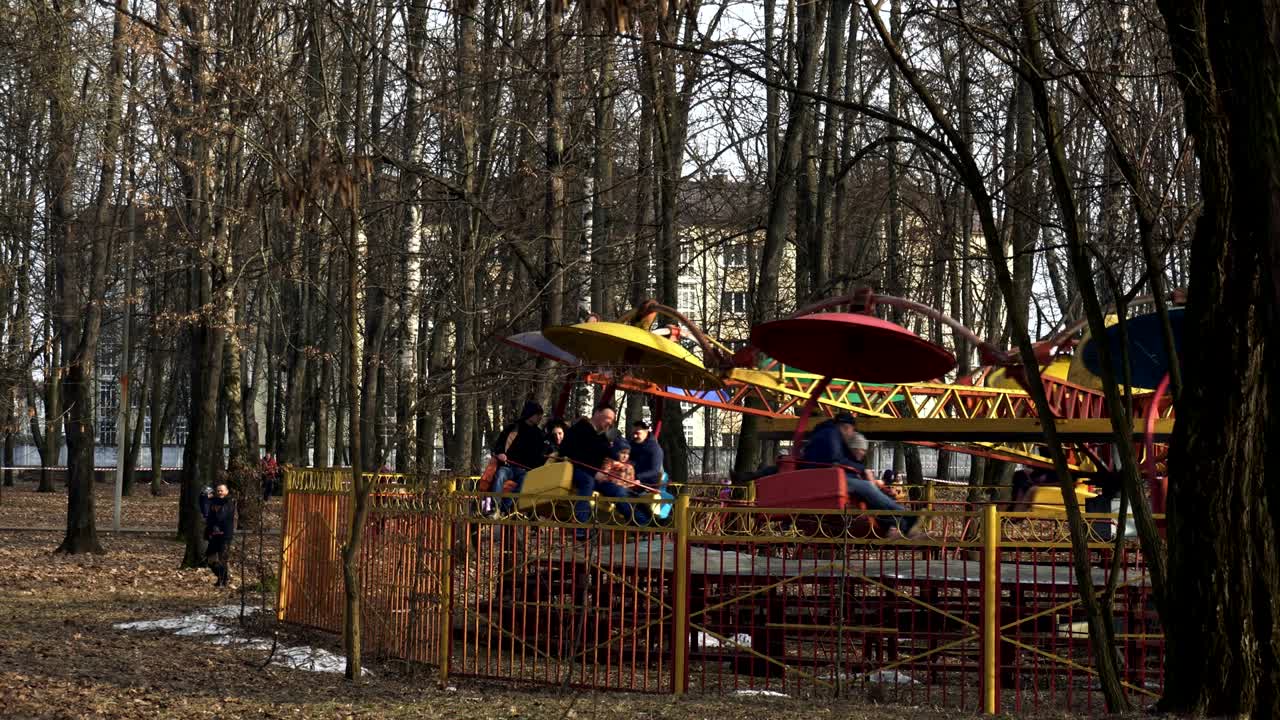People ride on the rainbow ride at the amusement park in the spring in BOBRUISK, BELARUS 03.09.19. Happy people spin on the colorful attraction at the amusement park in the open air.