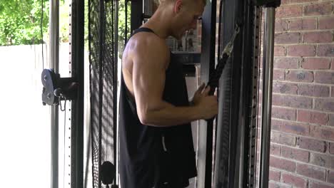 Muscly-man-in-home-gym-exercising-cable-tricep-push-downs