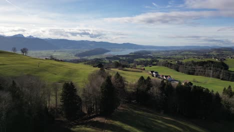 picturesque panning drone shot of small village in hillside valley with mountainous background, switzerland