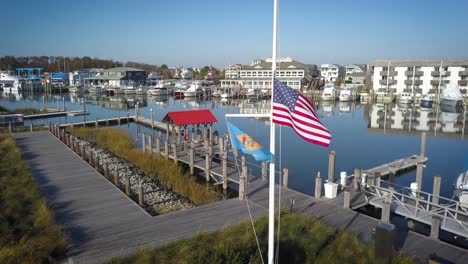 american flag blowing in the wind drone spin around it autumn day lewes delaware harbor boats in background