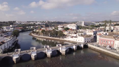 People-walking-at-Ponte-antiga-de-Tavira,-Roman-Bridge,-aerial-forward-view