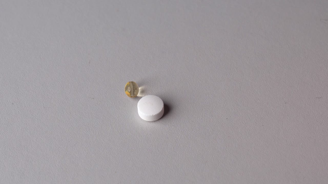 persona usa los dedos para tomar pastillas de vitaminas y cápsulas de la mesa gris