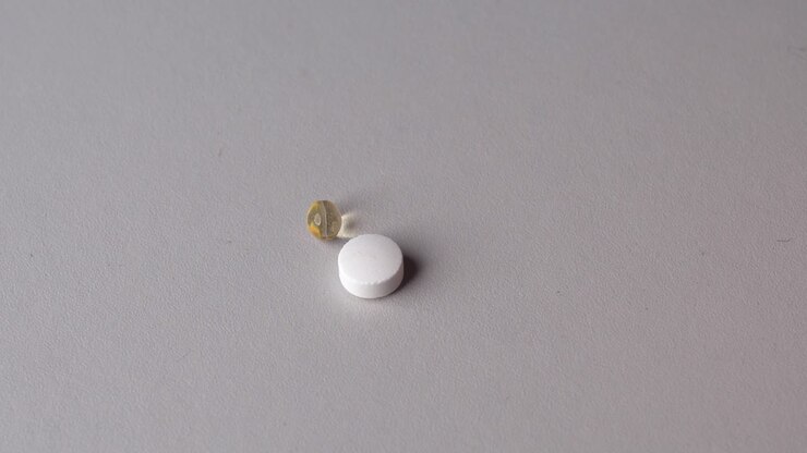 Person use fingers to take vitamin pills and capsules from grey table