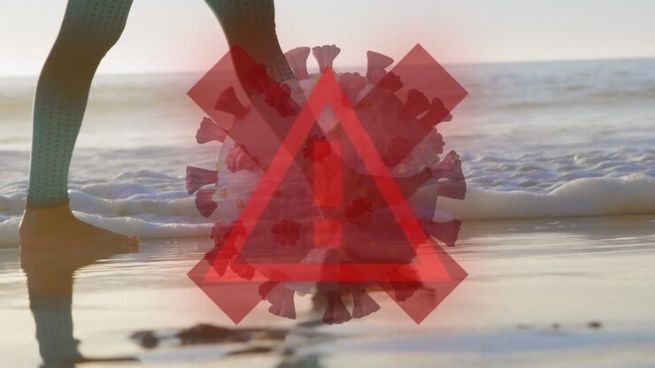 Animation shows Covid-19 warning over beachgoer, highlighting pandemic.