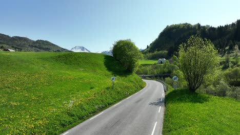 Roadsigns-in-Norway-cancelling-60-kmh-limit-and-enforcing-maximum-80-kilometers-an-hour---Aerial-of-roadsigns-and-road-at-idyllic-spot-surrounded-my-freen-fields