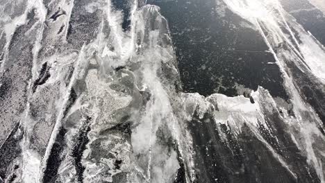 Drone-footage-of-a-frozen-lake,-capturing-intricate-ice-patterns-and-cracks-from-above,-highlighting-nature's-abstract-artistry