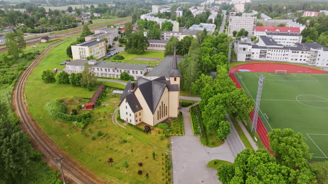 Smooth aerial orbit reveals church, green surroundings and Olaine skyline
