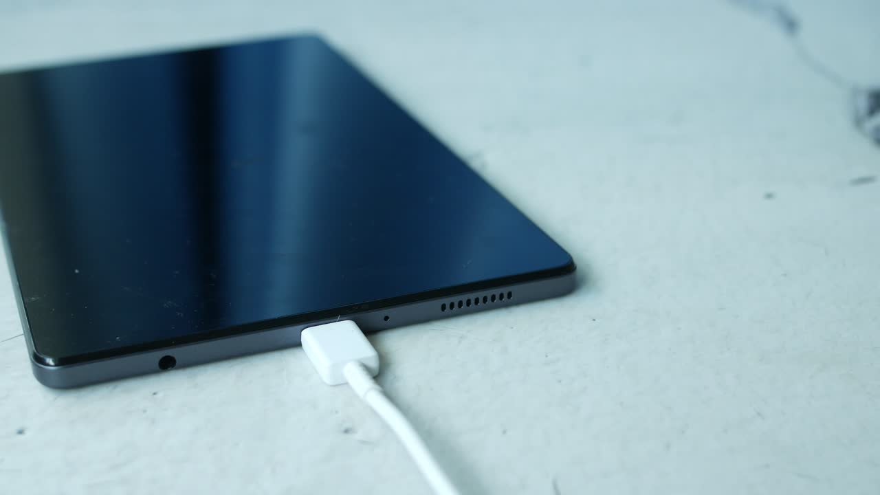 Recharge d'une tablette numérique avec un câble sur fond blanc
