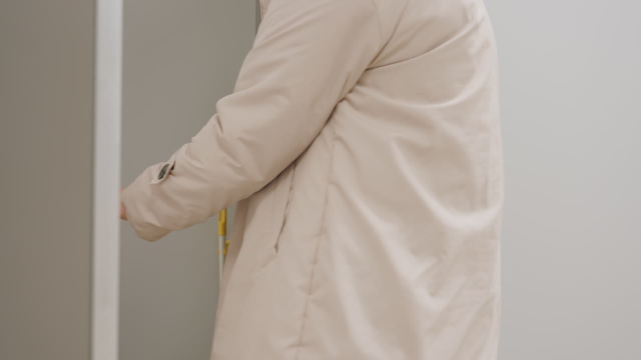 Side view of businesswoman opening door with metal handle, entering corridor with professional gesture, light reflecting on surface, daily routine moment symbolizing workplace environment