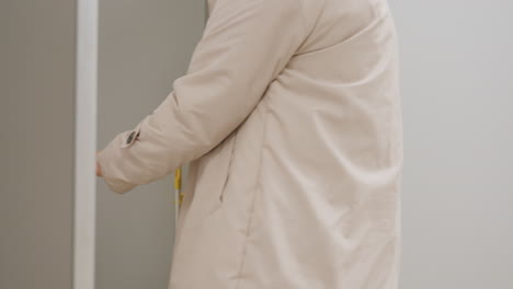 side view of businesswoman opening door with metal handle, entering corridor with professional gesture, light reflecting on surface, daily routine moment symbolizing workplace environment