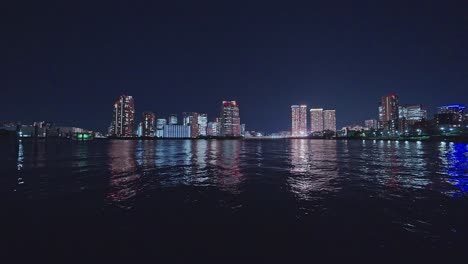 Night-light-Tokyo,-Tsukuda,-Toyosu-skyscrapers-and-bridge-the-Sumida-River-Yakatabune,-pleasure-boat