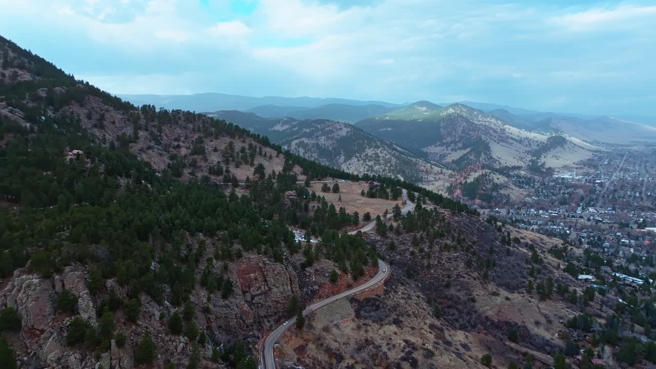 Slow tracking aerial of Boulder Flatirons rugged cliffs and deep green forestry below