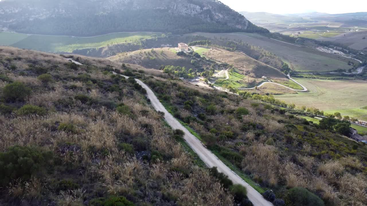 햇볕이 잘 드는 계곡에 있는 고대 그리스 사원이 내려다보이는 먼지 투성이의 낮은 비행