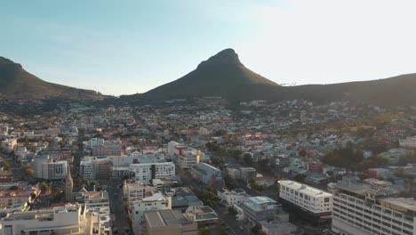aerial drone view showcases crowded cityscape nestled beside majestic arid mountains under clear blue sky in iceland. the rugged mountain terrain contrasts with the dense urban sprawl below