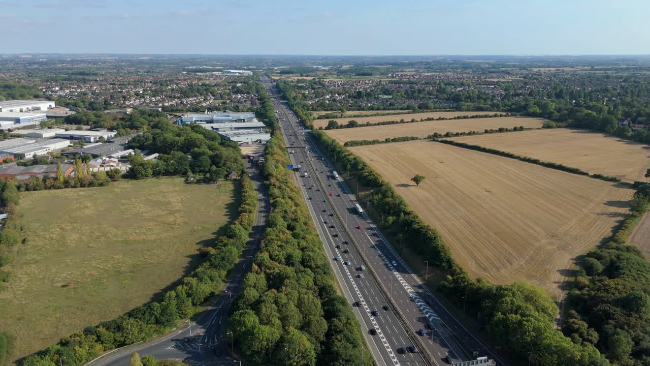 Drone aerial perspective of M1 highway transport corridor with surrounding warehouses, industrial buildings and distribution near Leicester England UK