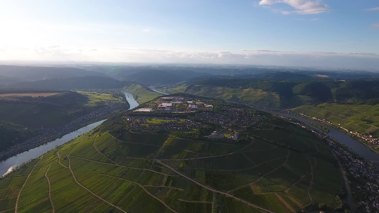 Drone aerial view of hop growing hill with village on top and a river bellow