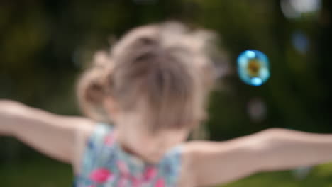 Fröhliches-Kleines-Mädchen,-Das-Spielerisch-Seifenblasen-Fängt,-Die-Mit-Einem-Niedlichen-Kind-Schwimmen,-Das-Spaß-Daran-Hat,-Blasen-Im-Sonnigen-Park-Zu-Platzen,-Unbeschwertes-Kindheitsspiel-4k